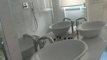 A bathroom with a glass shower enclosure, two sinks, and a mirror.