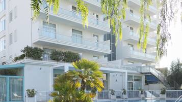 Un hotel moderno con piscina, immerso nel verde e affiancato da un edificio a più piani.