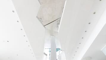 A modern interior with a high ceiling, recessed lighting, and a central structural column.