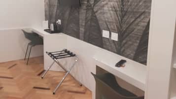 A modern room with a white desk, a flat-screen TV, and a wall-mounted artwork of leaves.