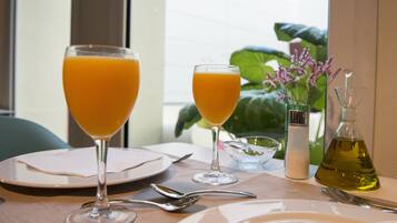 Een tafel gedekt met twee glazen sinaasappelsap, een zout- en peperstelletje, een kleine kom en een fles olijfolie.