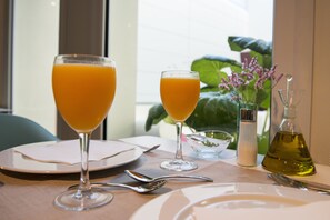 A table set with two glasses of orange juice, a salt and pepper shaker, a small bowl, and a bottle of olive oil. - La Alcoba del Agua Hotel Boutique (Sanlucar de Barrameda)