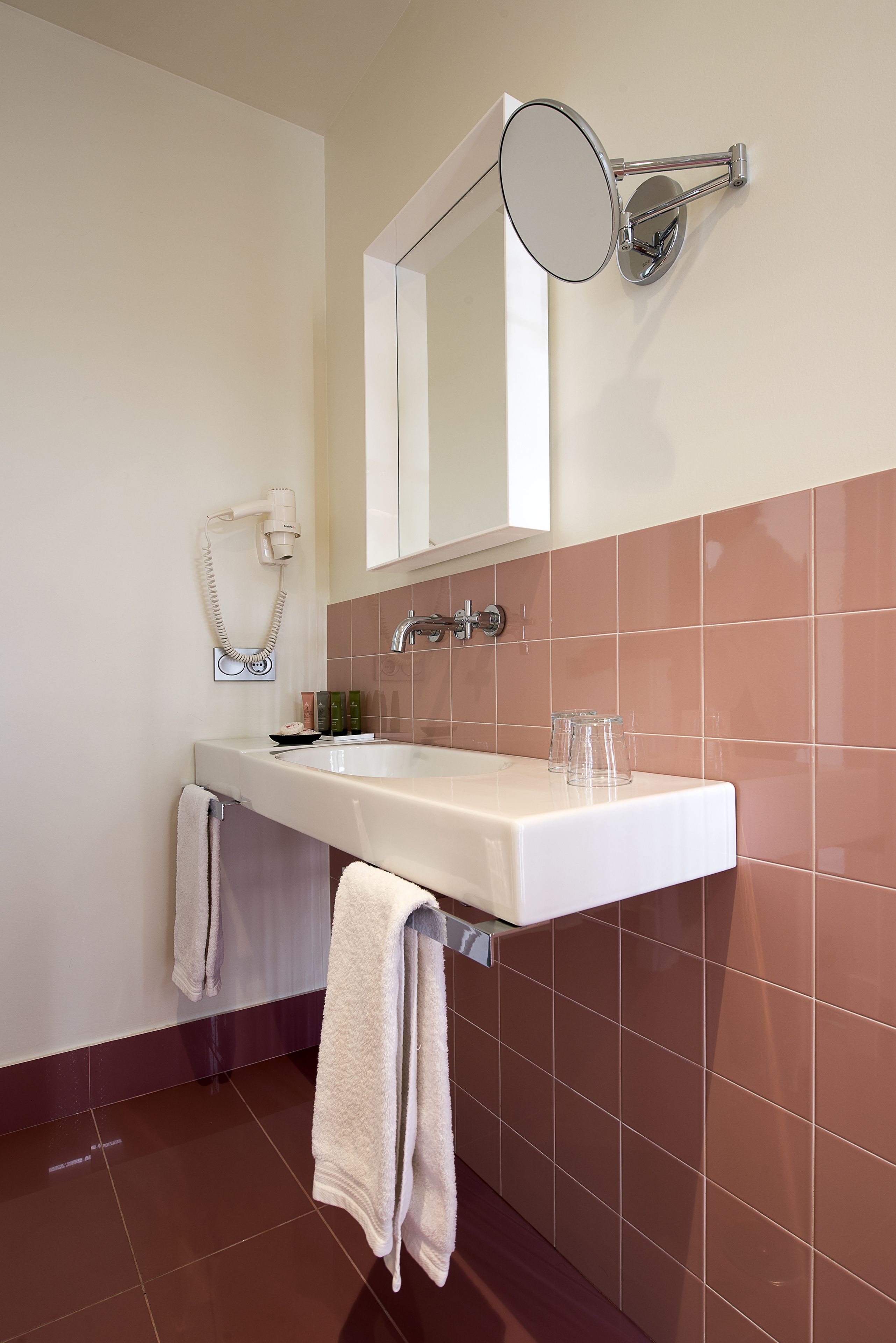 Une salle de bain avec un lavabo blanc, un miroir et un porte-serviettes.