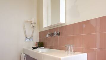 Une salle de bain avec un lavabo blanc, un miroir et un porte-serviettes.
