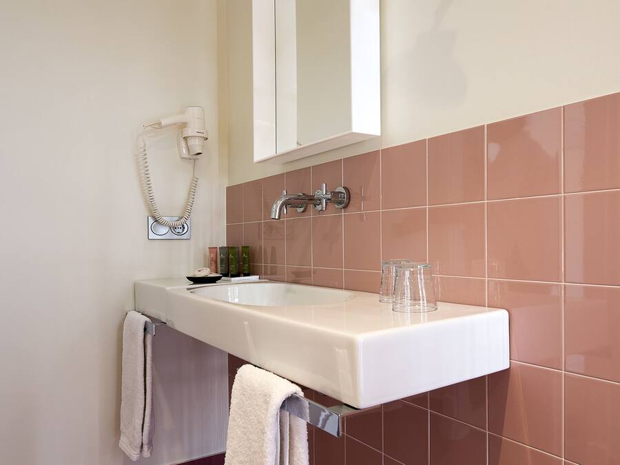 Une salle de bain avec un lavabo blanc, un miroir et un porte-serviettes.