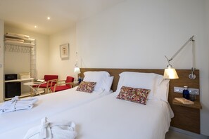 A hotel room with two beds, a desk, a chair, a small table, a lamp, and a nightstand. - La Alcoba del Agua Hotel Boutique (Sanlucar de Barrameda)