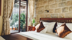 Un dormitorio con pared de piedra, cabecera de madera y ventana con cortinas.