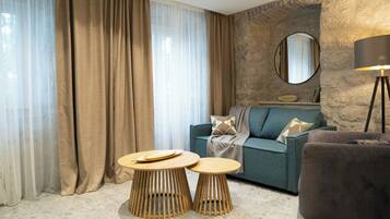 Un salon moderne avec un canapé, deux petites tables en bois, une lampe et un mur d’accent en pierre.