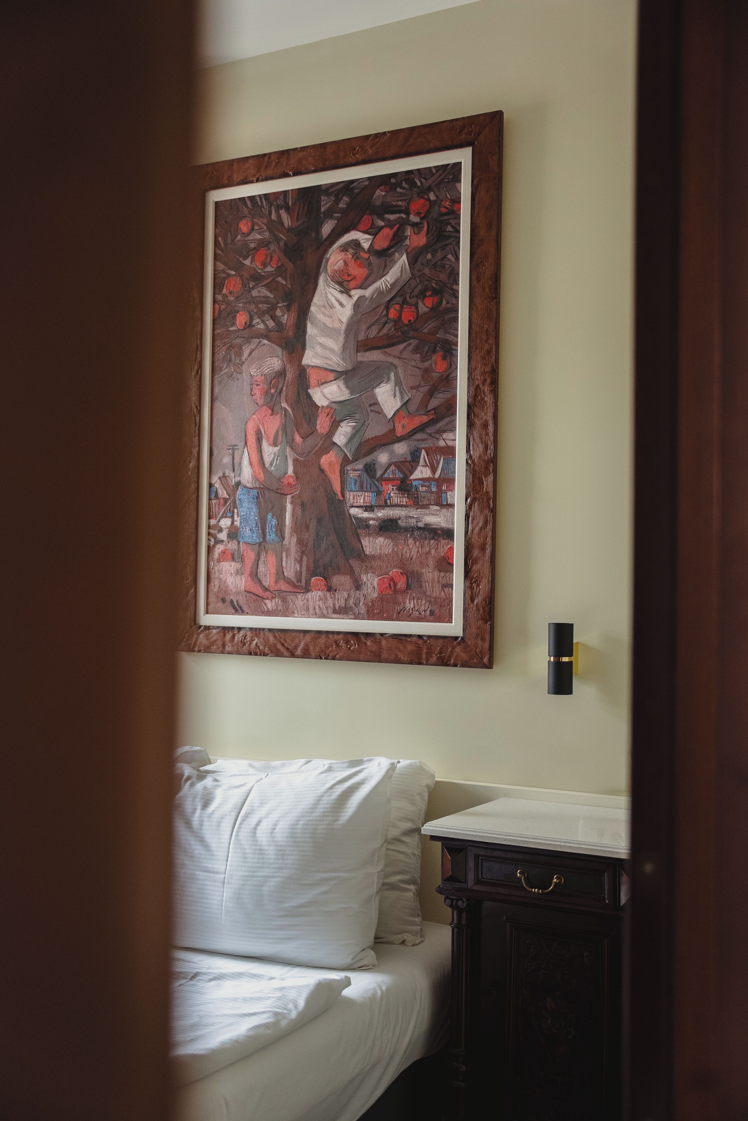 A bedroom with a bed, a nightstand, and a wall-mounted painting.