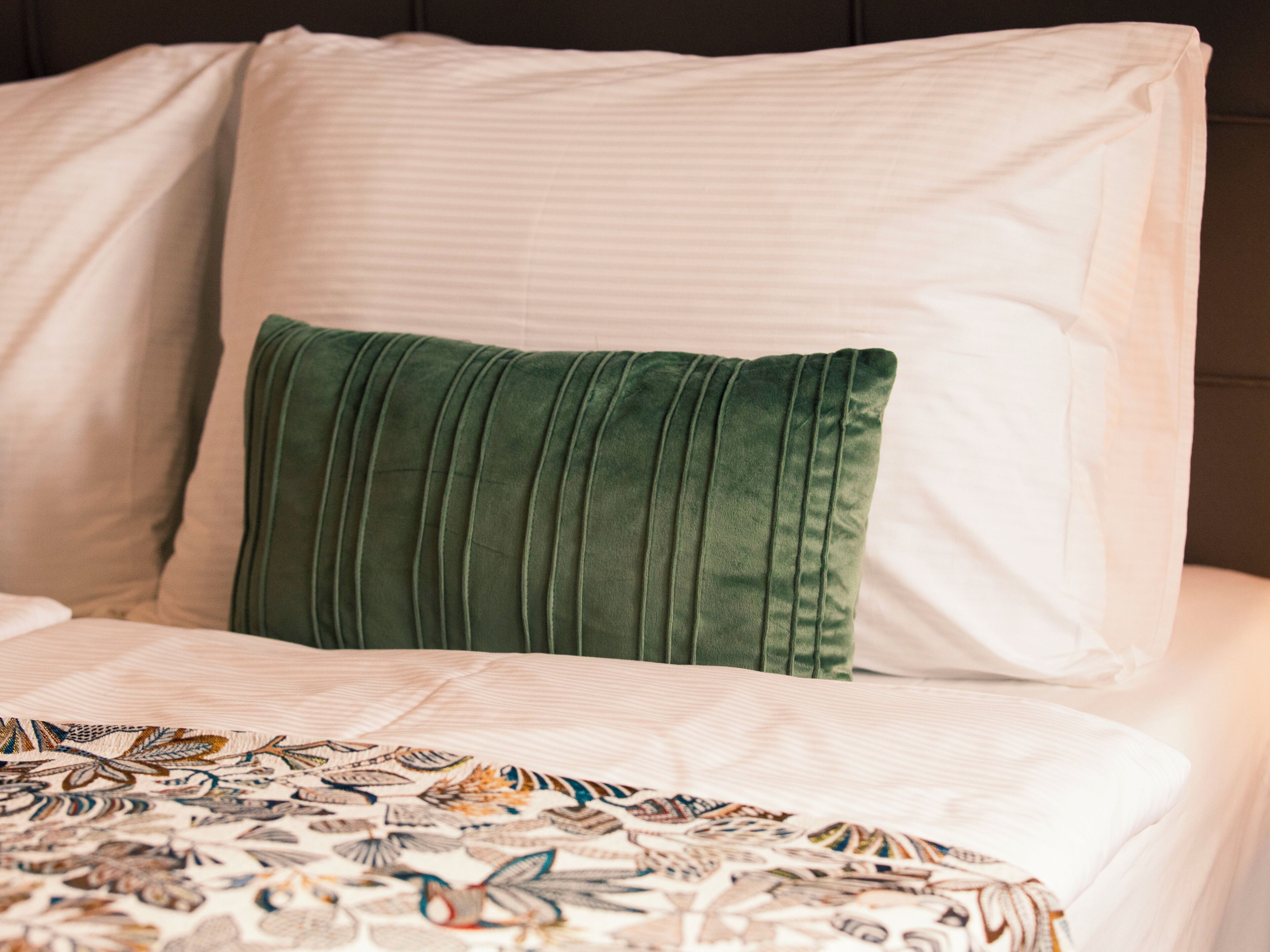 Un lit avec une couvre-lit à motifs et un oreiller vert.