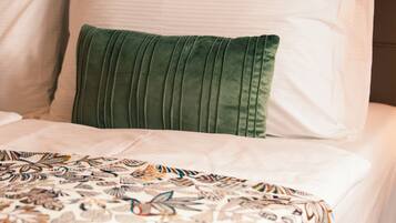 Un lit avec une couvre-lit à motifs et un oreiller vert.