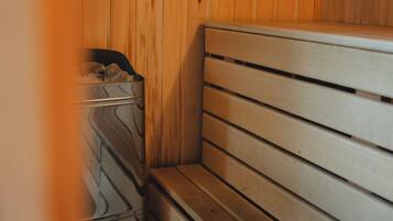 A wooden bench with a metal trash bin in a sauna room.