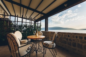 Un espacio de estar al aire libre cubierto, con mesa, sillas y vista al mar.