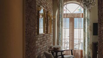 A hallway with a brick wall, a wooden chair, a table, and a chandelier.