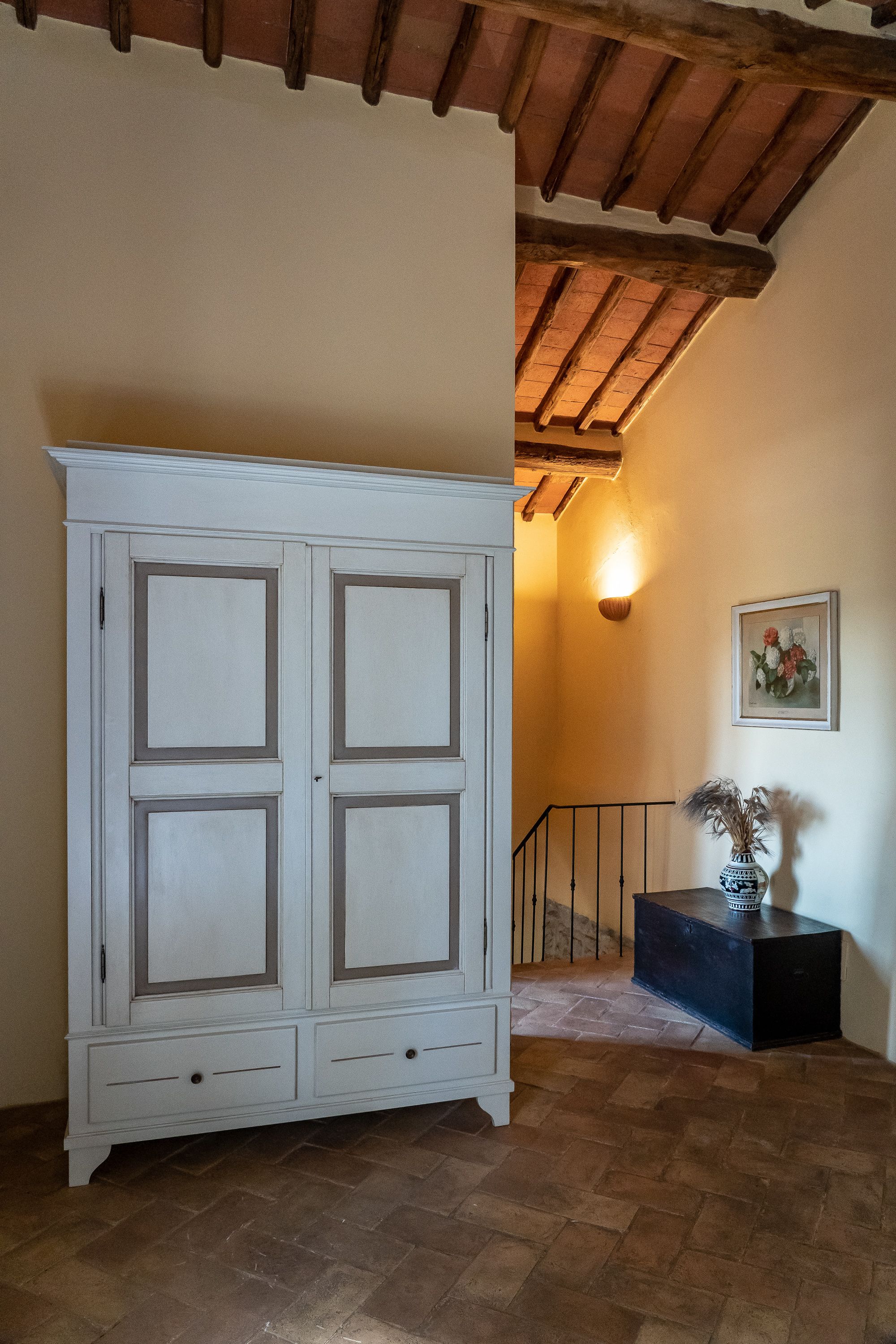 Une pièce avec une grande armoire blanche, un escalier et un luminaire fixé au mur.