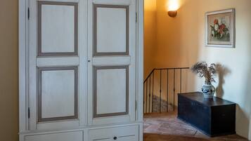 Une pièce avec une grande armoire blanche, un escalier et un luminaire fixé au mur.