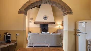 Une cuisine avec une arche en briques, un four encastré, un réfrigérateur et une table à manger.