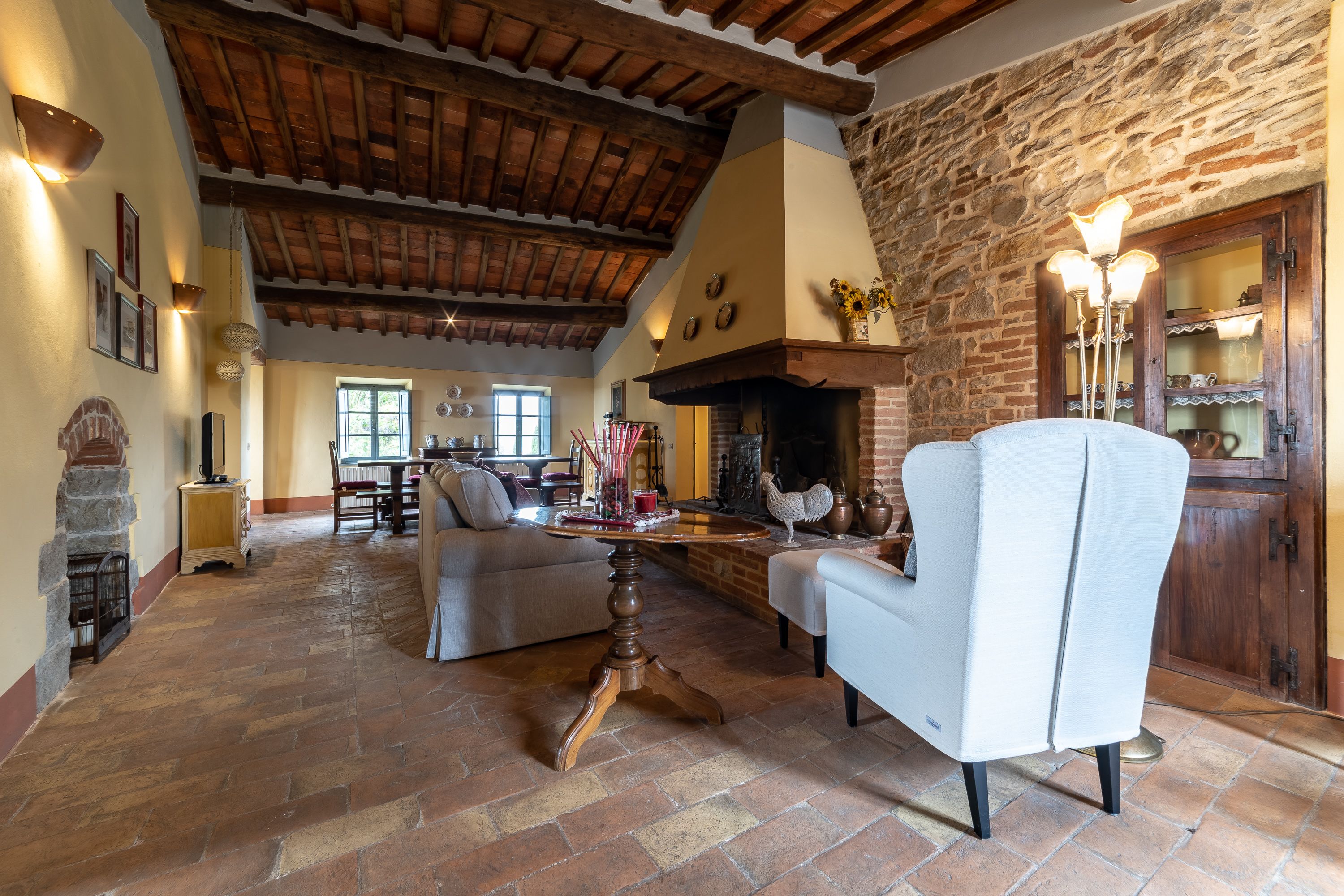 A spacious living room with a stone fireplace, wooden beams, and a cozy seating area.