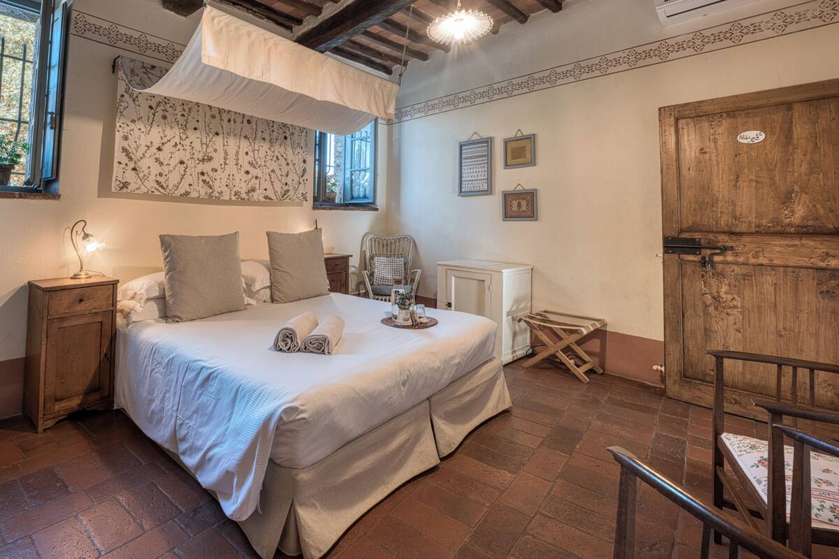 A bedroom with a bed, bedside tables, a chair, a radiator, and a wooden door.