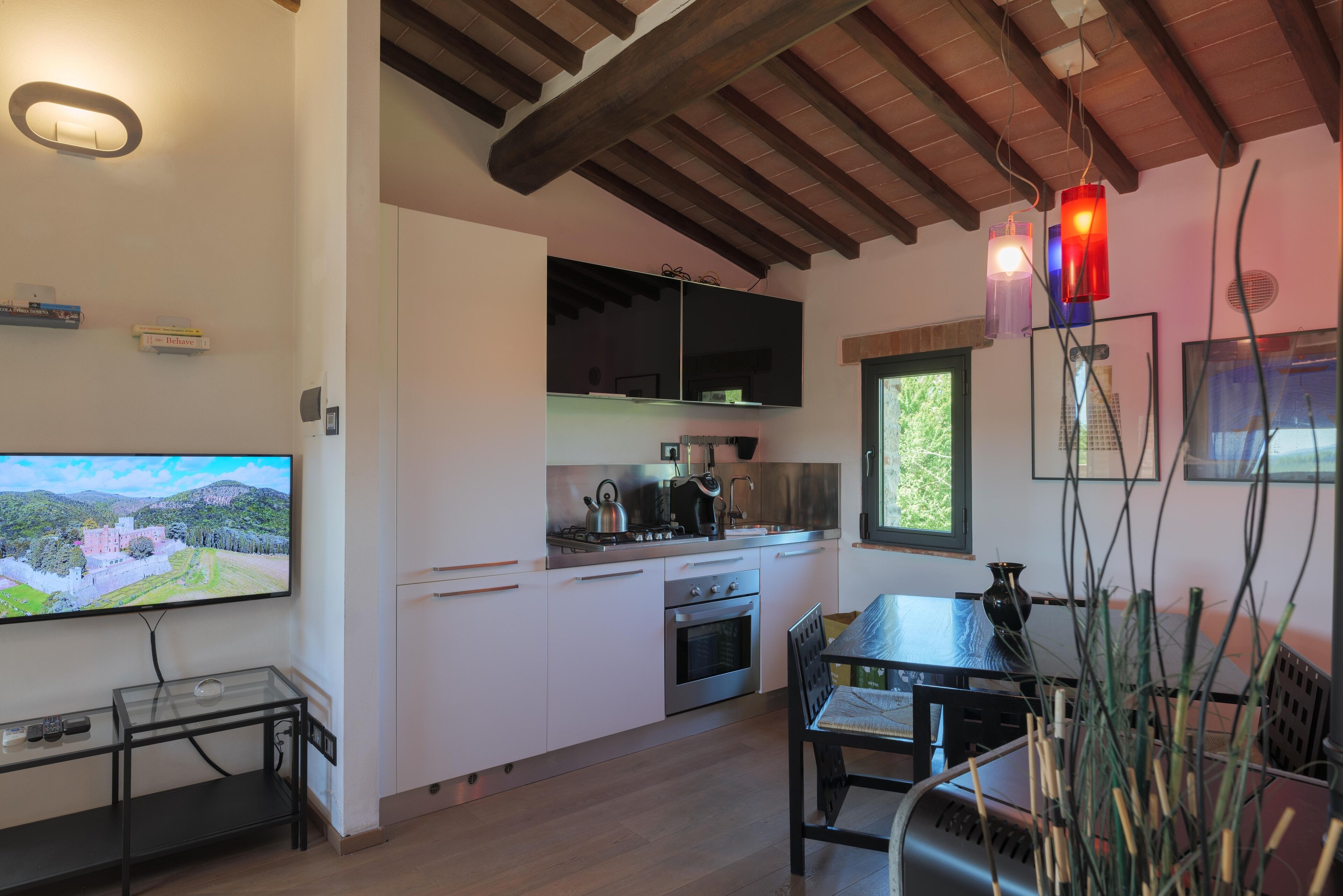 A modern kitchen with white cabinets, a built-in oven, and a dining area with a table and chairs.