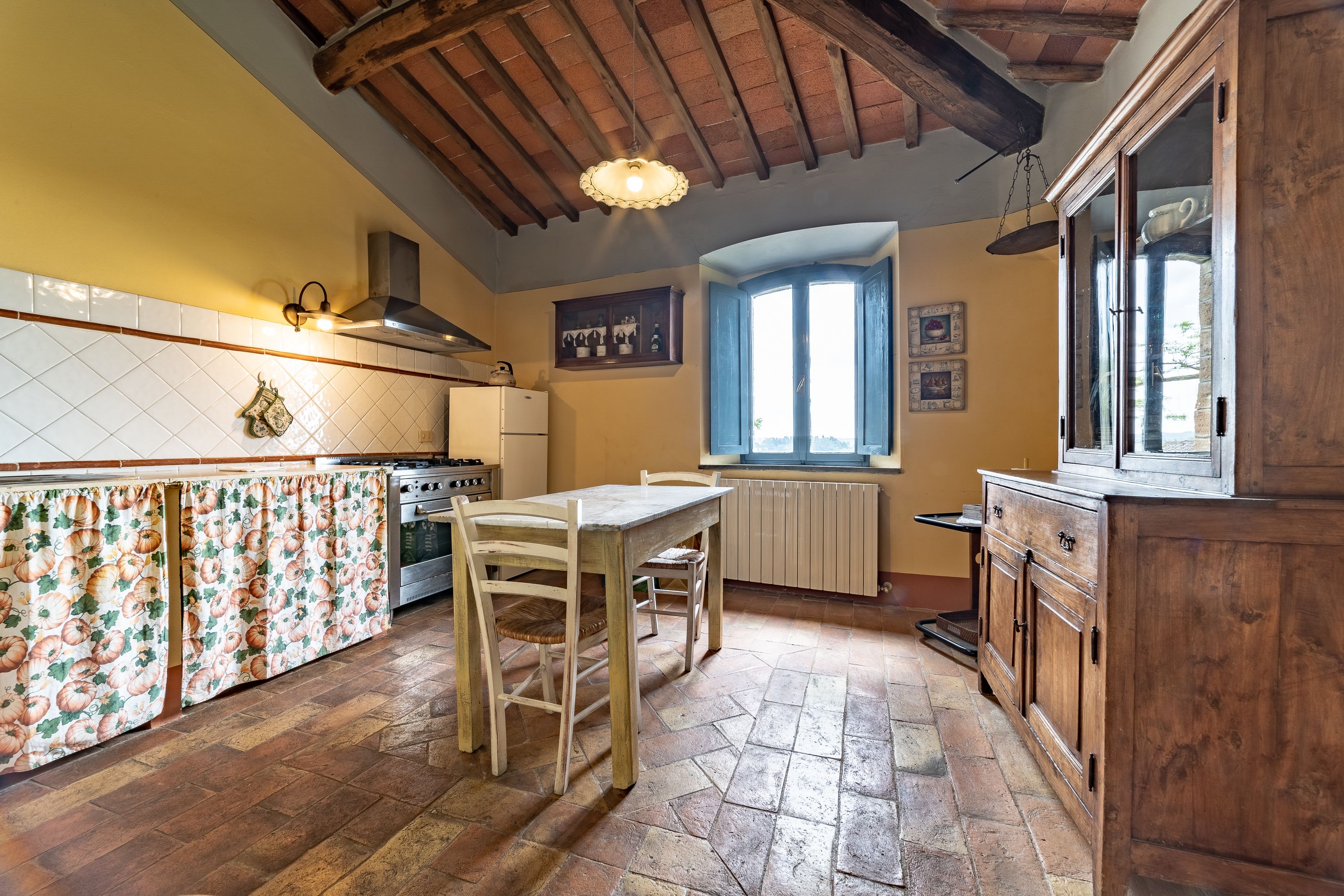 A kitchen with a wooden table, chairs, a stove, and cabinets.