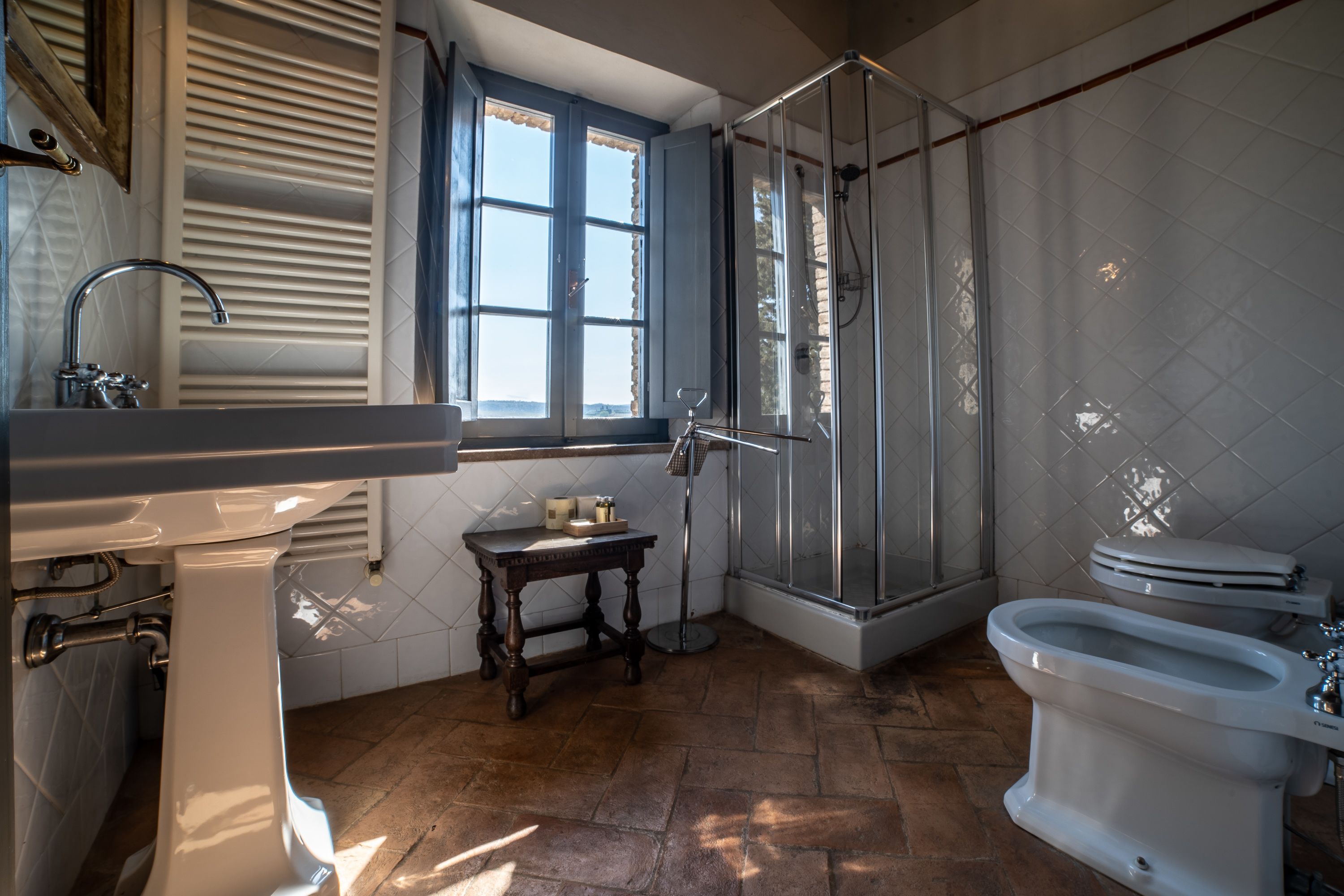 Een badkamer met een douche, toilet, toiletbrons en wastafel.