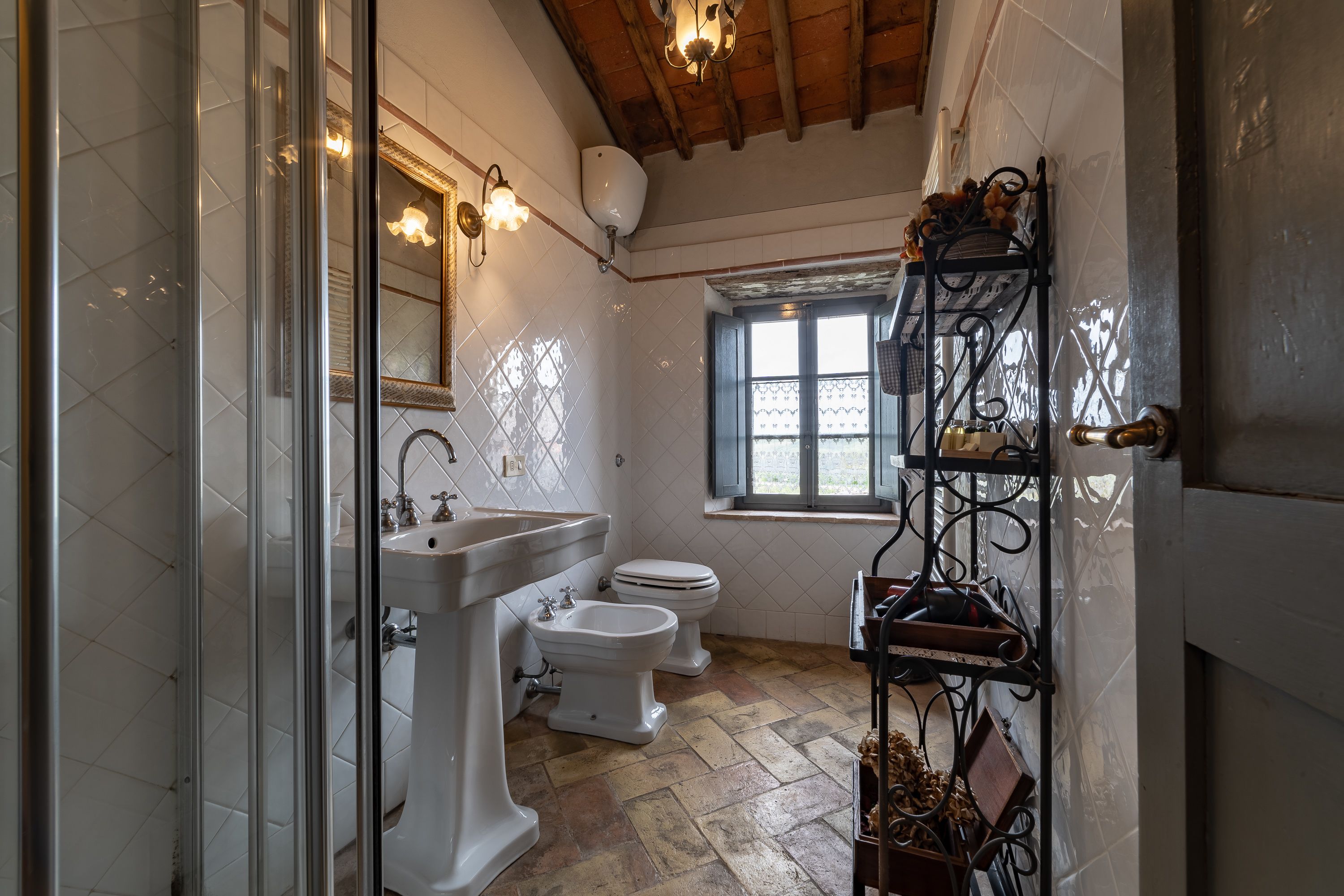 A bathroom with a sink, bidet, and toilet. There is a window with a view of the outside.
