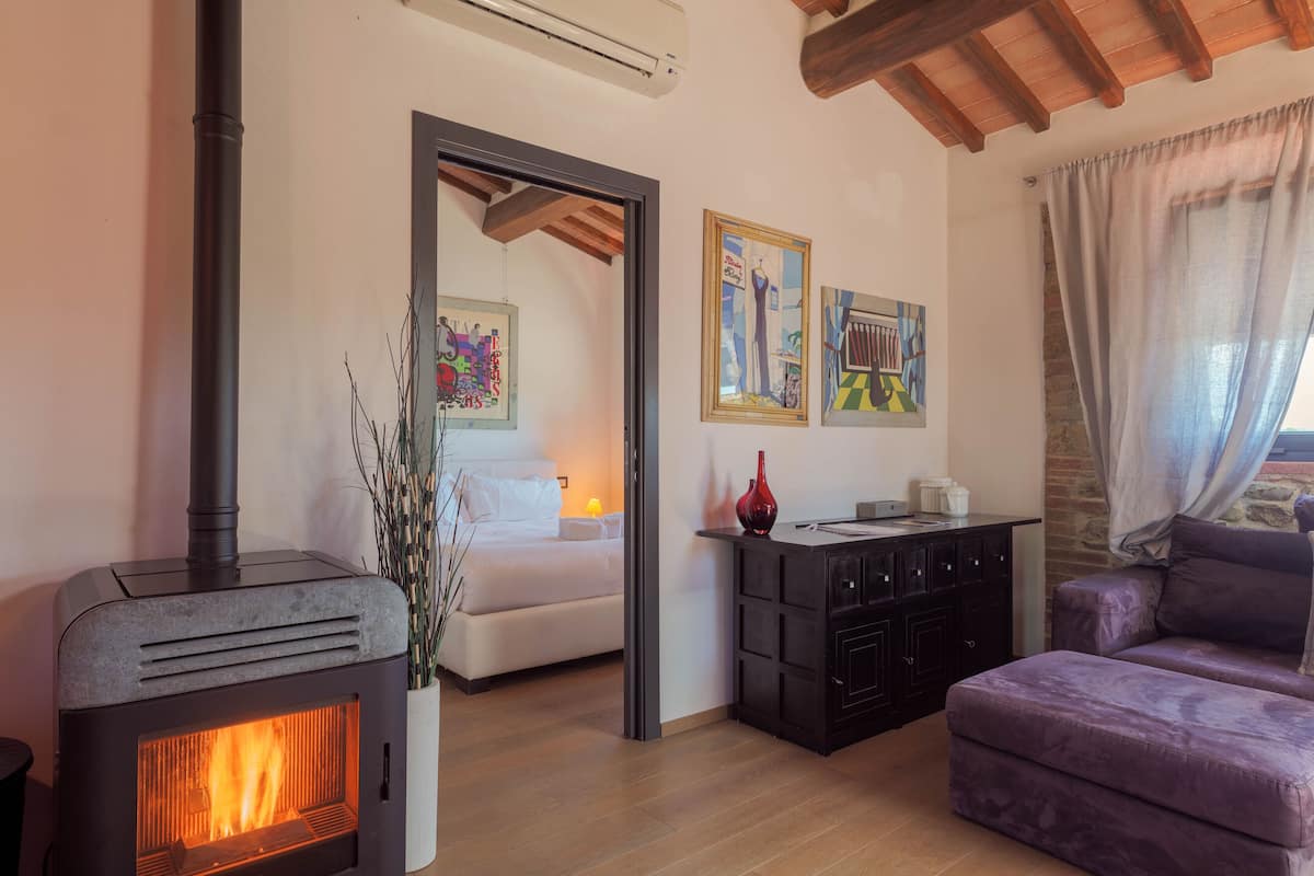 A cozy room with a wood-burning stove, a bed, a dresser, and artwork on the walls.