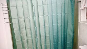 Une salle de bain avec un rideau de douche, des toilettes et un porte-serviettes.