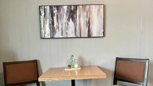 A dining area with a square table and two chairs with woven backs.