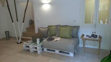 A living room with a sofa, a coffee table, a small table with decorative items, and a door with frosted glass panels.