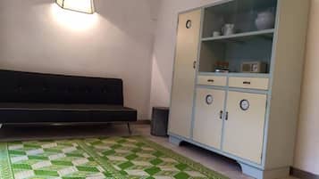 Una habitación con sofá, una vitrina y un tapete estampado.