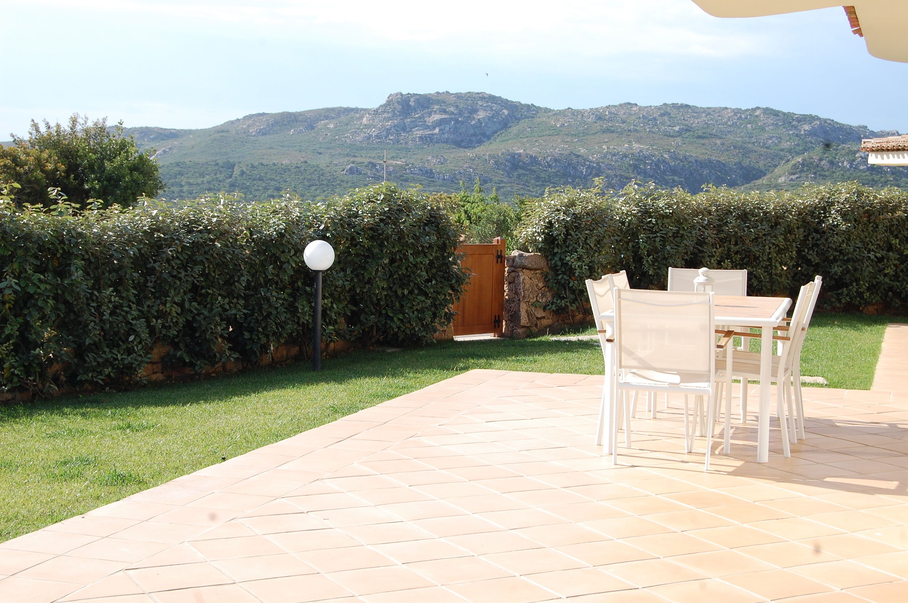 Un patio con una mesa y sillas, un muro de piedra y vistas a montañas.