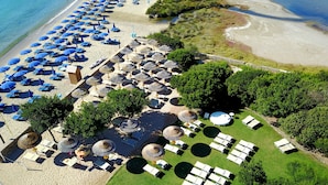 An aerial view of a beach resort with multiple sun loungers, umbrellas, and a grassy area with lounge chairs. - Le Saline Palau (Palau)