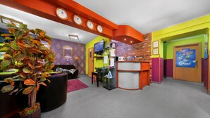 A brightly colored lobby with a reception desk, seating area, and a large potted plant. - Moon Hostel Kraków (Kraków)