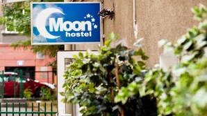 A hostel sign with a crescent moon and stars, a gated entrance, and potted plants. - Moon Hostel Kraków (Kraków)