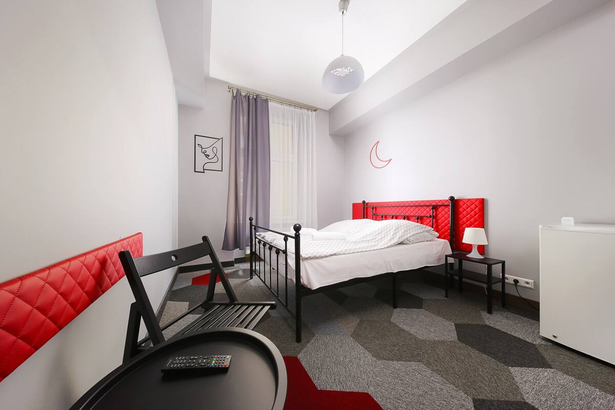 Una habitación de hotel moderna con una cama, un escritorio, una silla, una lámpara y un reloj de pared.