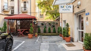 A hostel named 'Moon Hostel' with a red-roofed outdoor seating area, potted plants, and a car parked nearby. - Moon Hostel Kraków (Kraków)