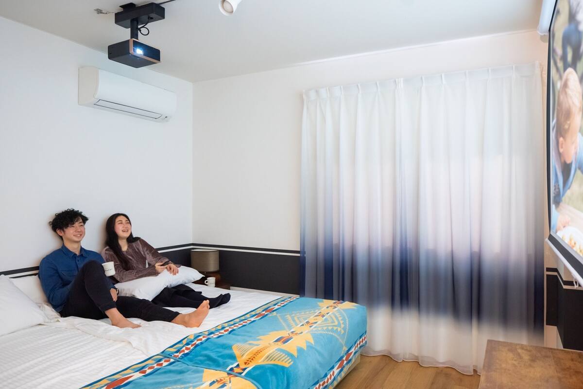 A hotel room with a bed, a TV, and a window with curtains.