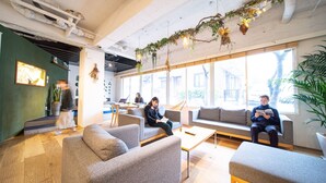 A modern lounge area with seating, large windows, and indoor plants. - Hotel Graphy Nezu (Tokyo)