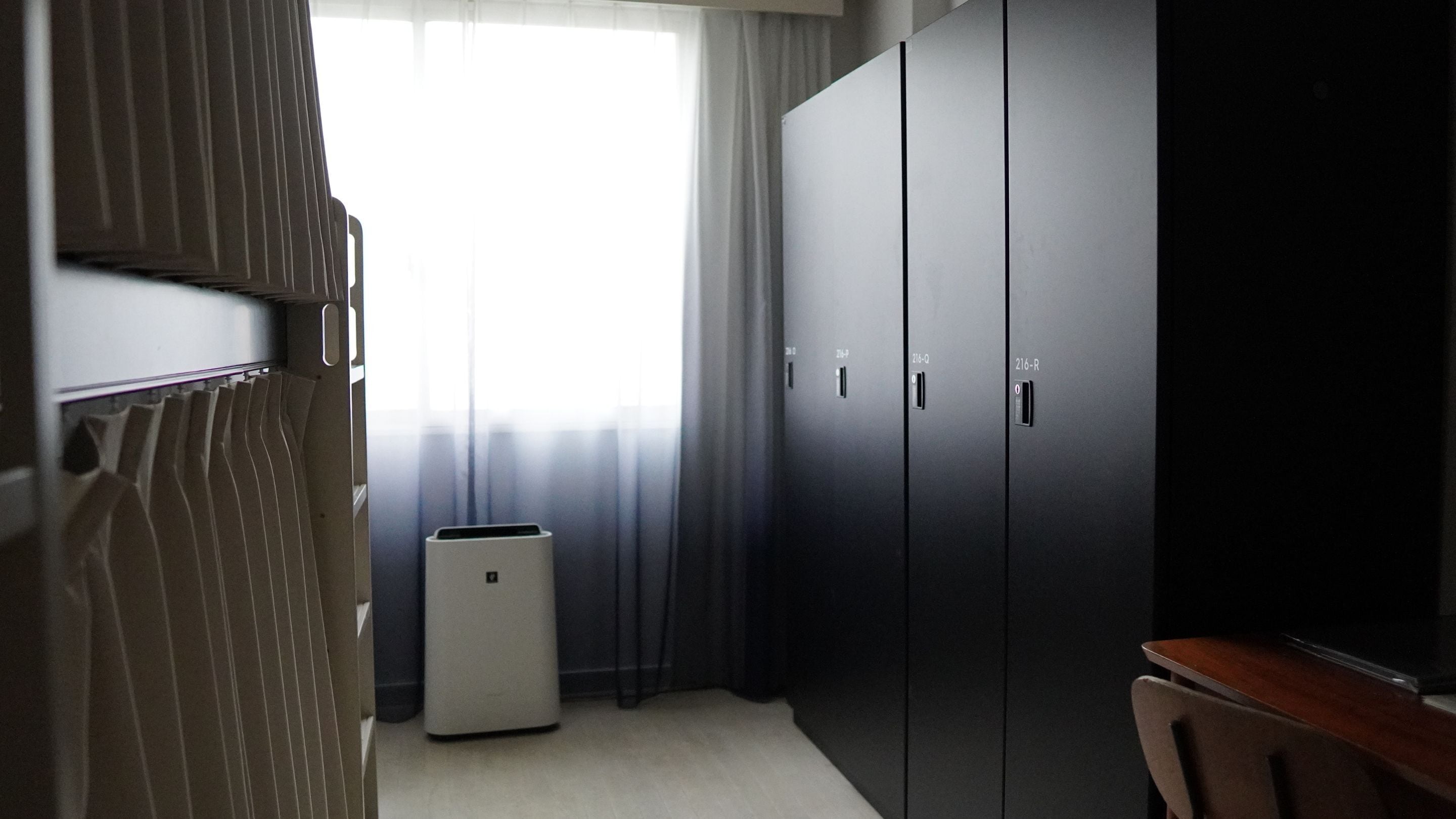 A hotel room with a bed, a desk, a chair, and a wardrobe.