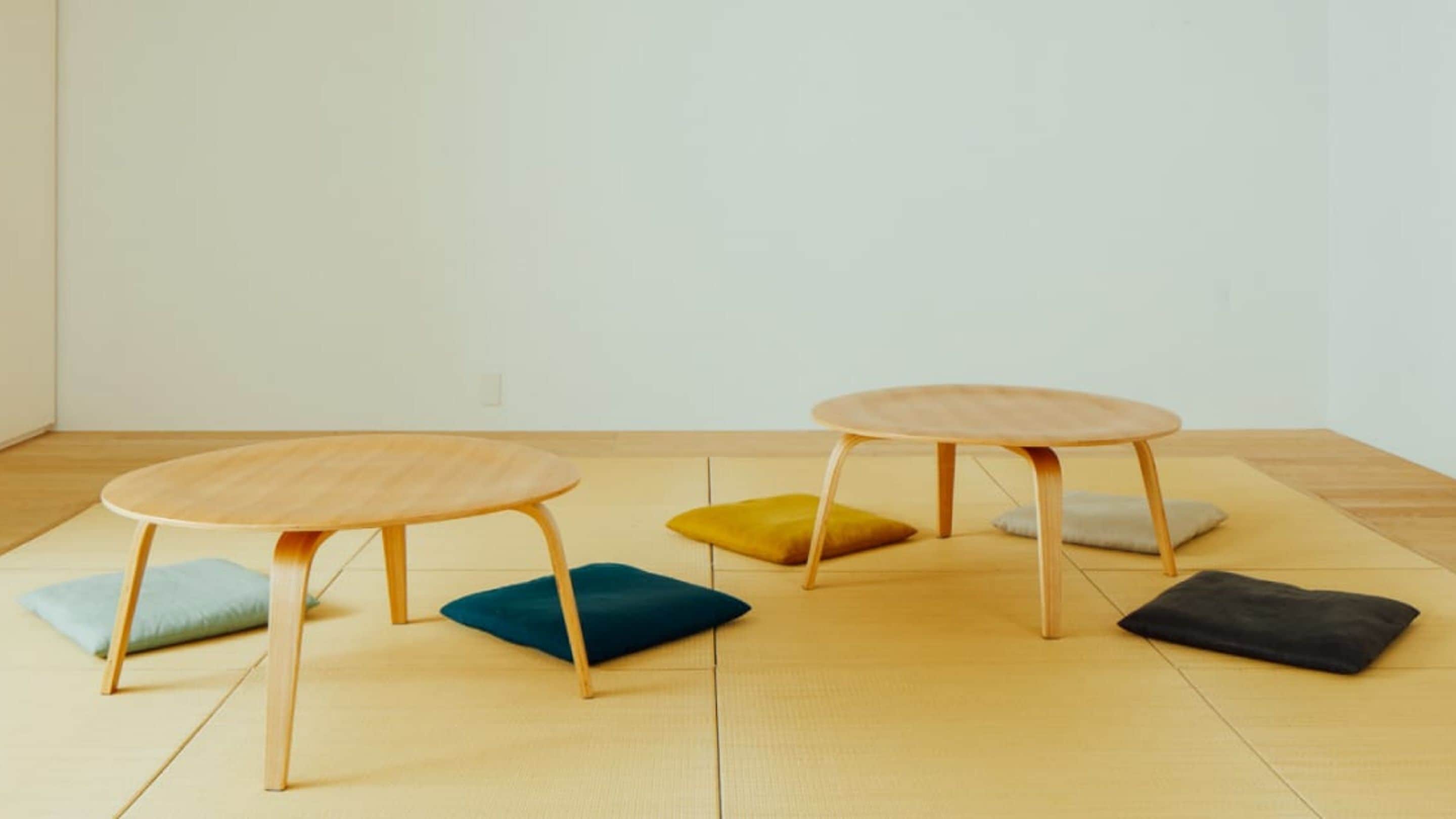 Two round tables with wooden legs and a tatami mat floor.