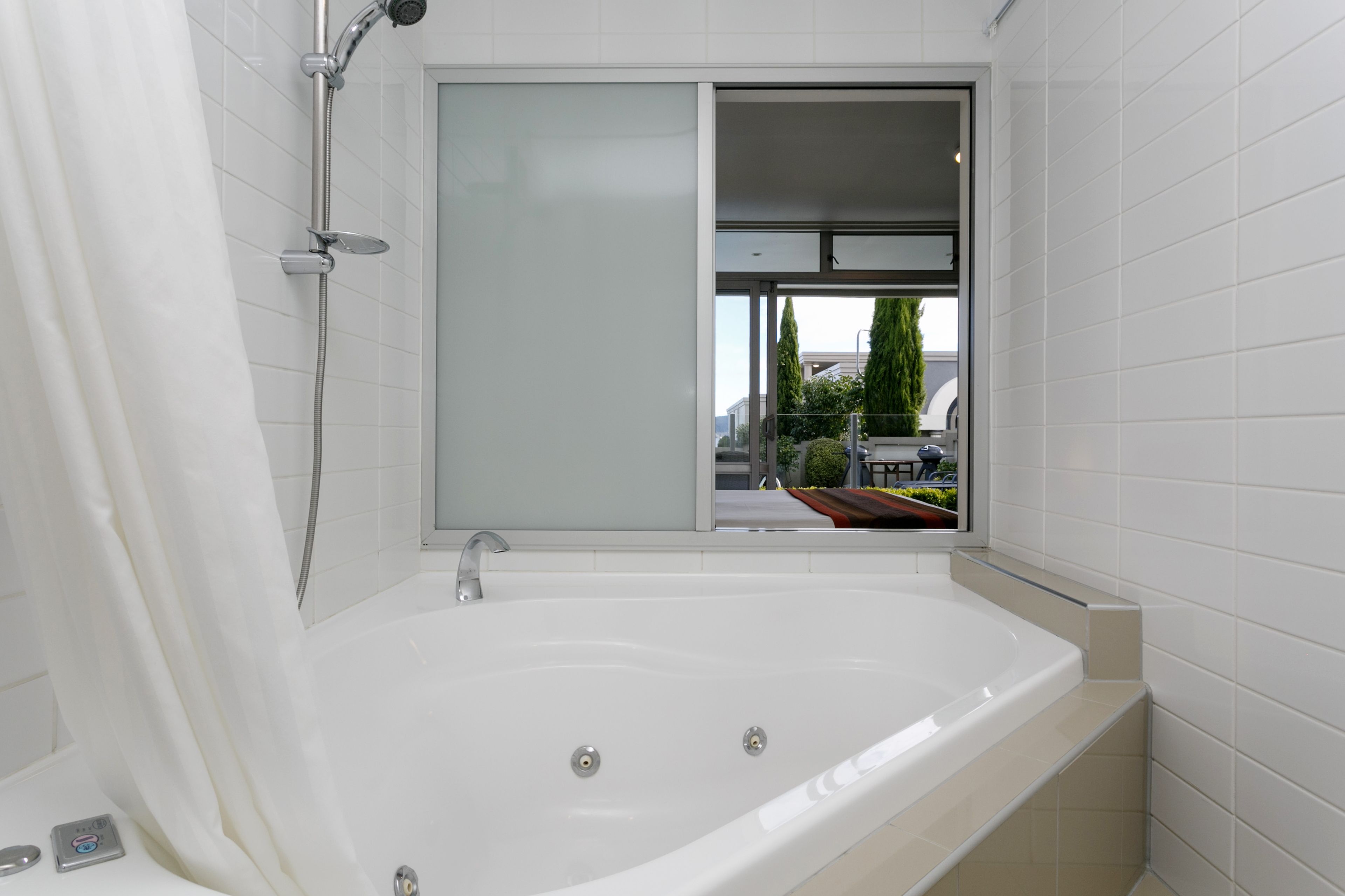 Un baño moderno con una bañera grande, un cabezal de ducha y una ventana con vistas al exterior.
