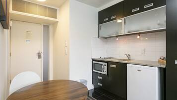Una cocina compacta con microondas, lavamanos y armarios negros.