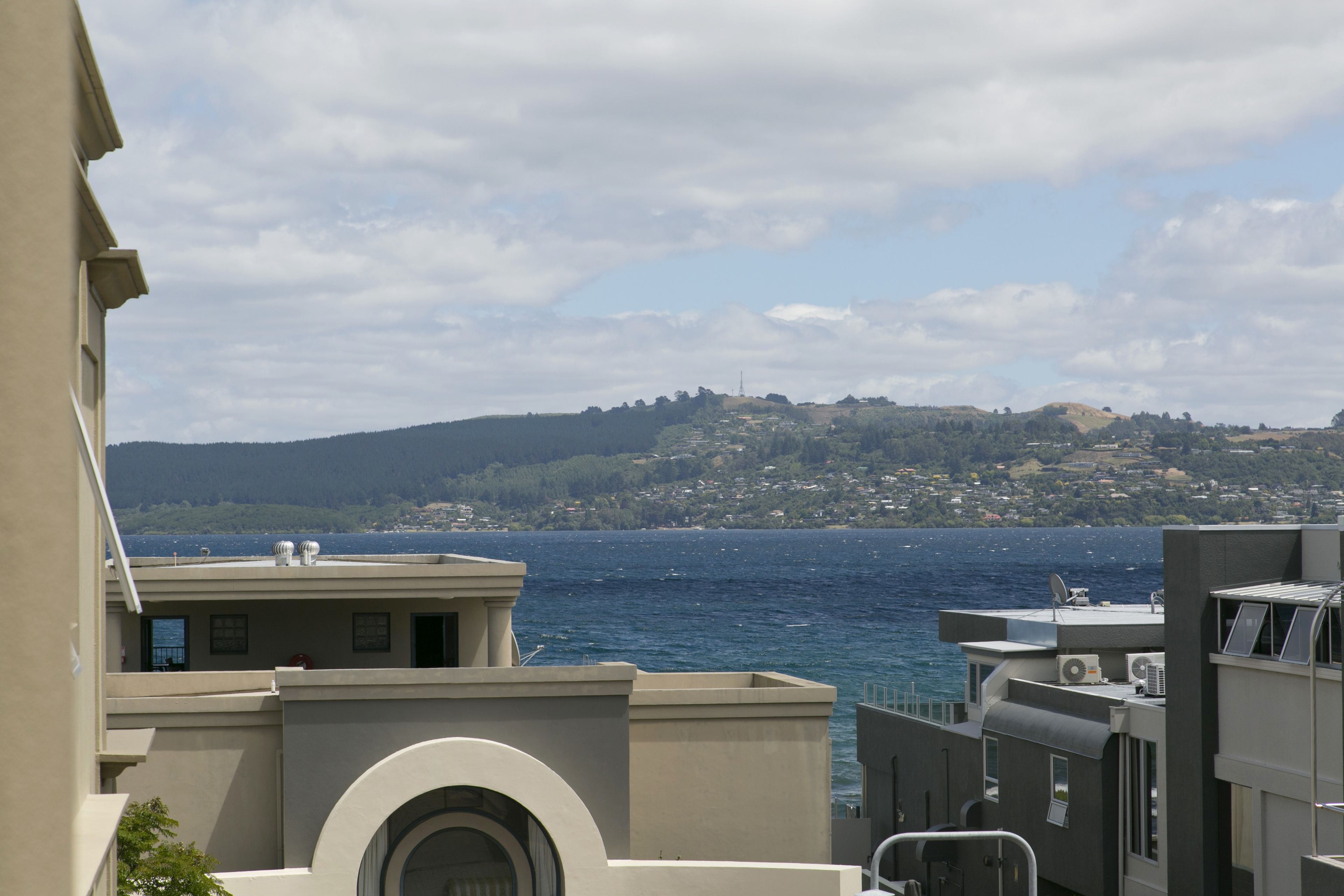 A coastal building with a view of the sea and a hilly landscape in the background.