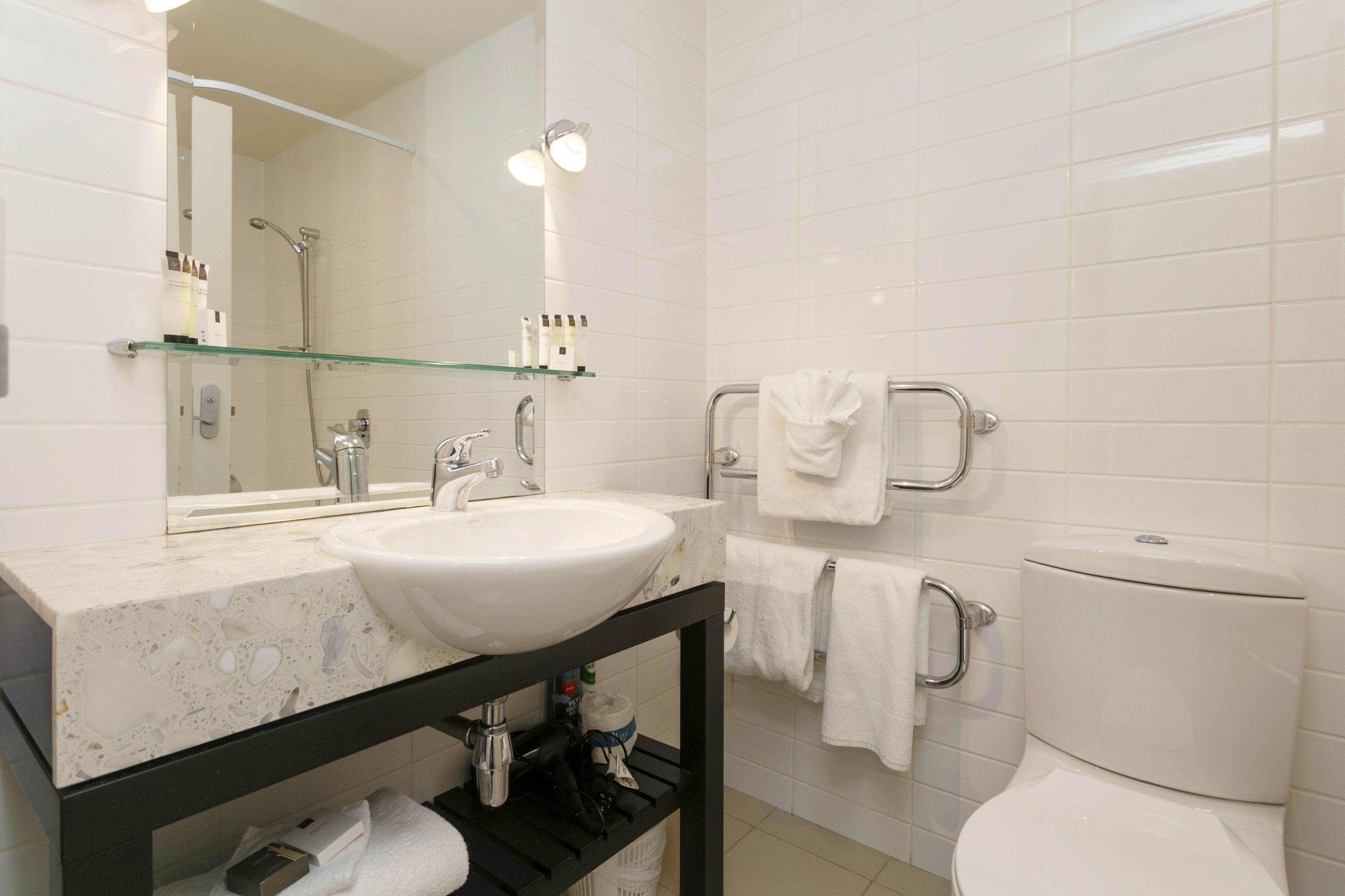 A modern bathroom with a white sink, mirror, and toilet.