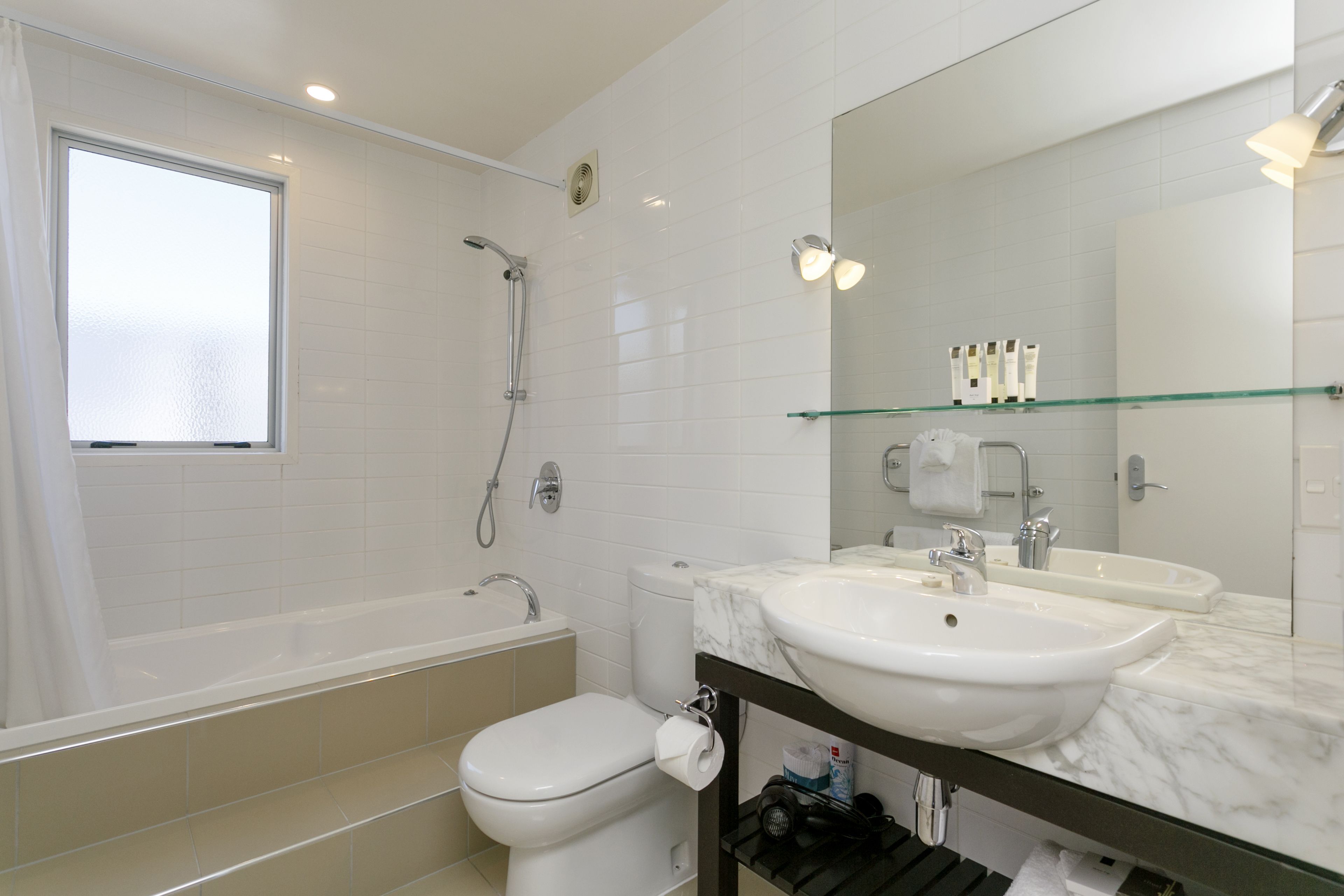 A modern bathroom with a bathtub, toilet, and dual sinks.
