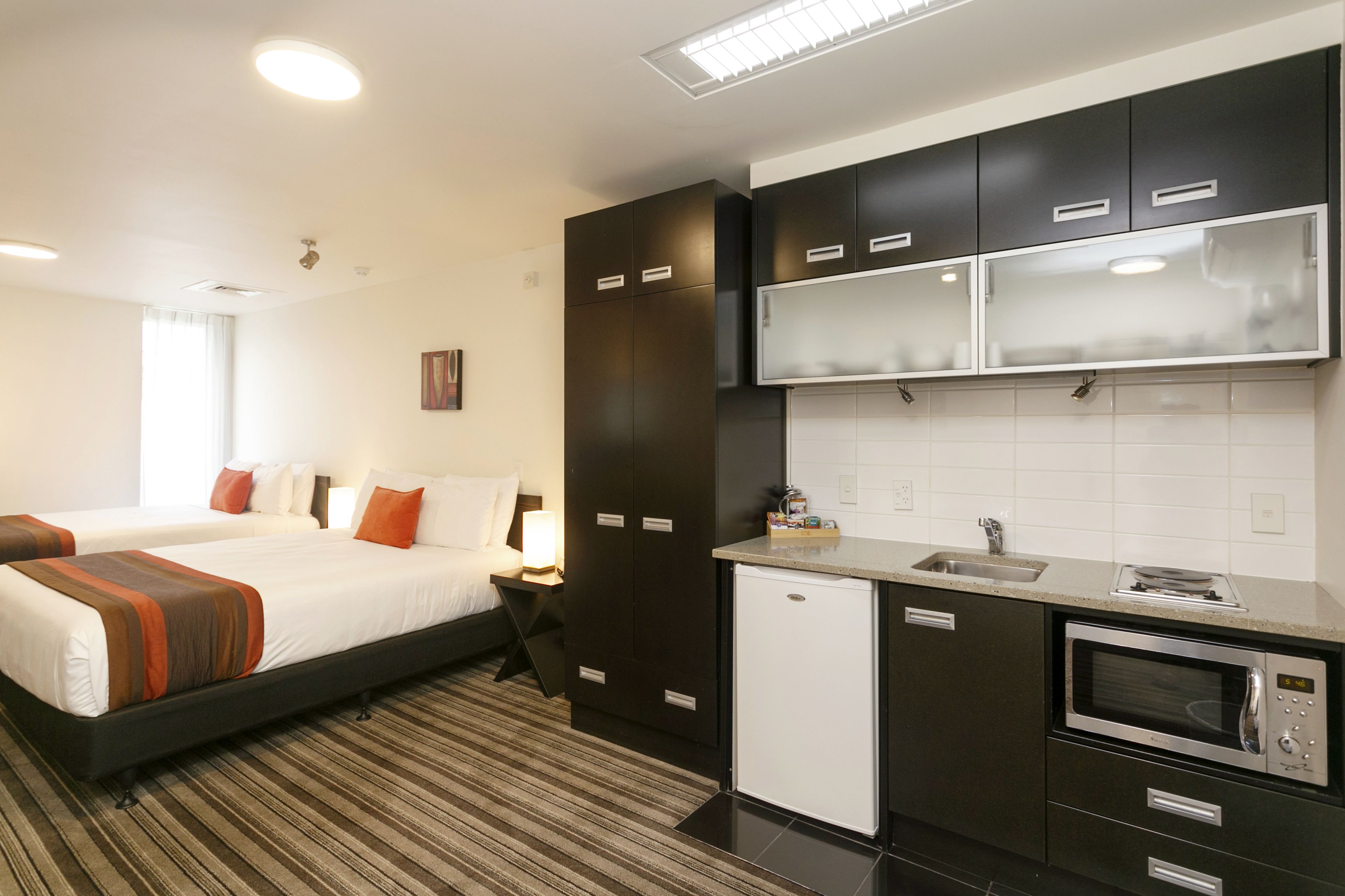 Une chambre d’hôtel avec un lit, une petite kitchenette et une salle de bain.