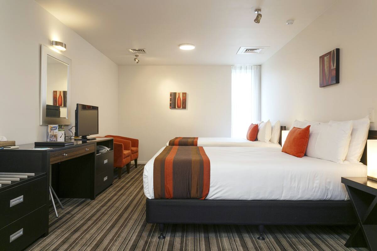 A hotel room with a bed, desk, chair, and a television.