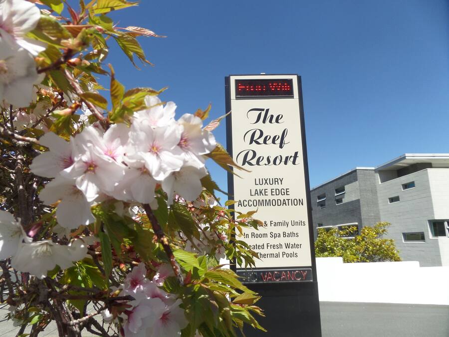 A sign for The Reef Resort, indicating it is a luxury lake edge accommodation with family units, spa baths, and thermal pools.